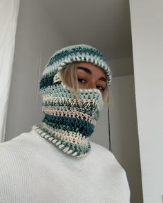 a woman with blonde hair wearing a crocheted hat and neck scarf in front of a mirror