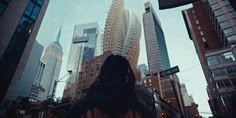 a person standing in the middle of a city street looking up at tall buildings and skyscrapers