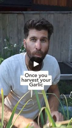 a man sitting in the grass with a sign that says, once you harvest your garlic