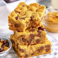 three pieces of cookie bars stacked on top of each other next to a bowl of chocolate chips