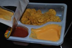 a plastic container filled with cheese and crackers next to ketchup on a table