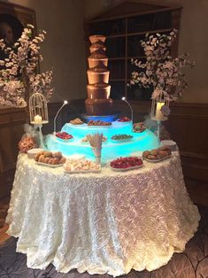 a table topped with lots of desserts and pastries on top of a white table cloth