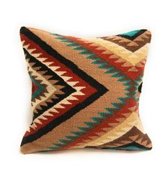 a decorative pillow with multicolored designs on the front and back, sitting on a white surface