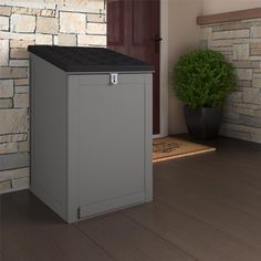 a gray trash can sitting on top of a wooden floor next to a brick wall