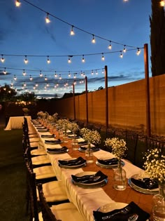 a long table is set with plates and place settings for an outdoor dinner or party