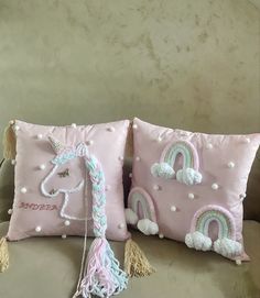 two decorative pillows on a couch with tassels and pom poms attached to them