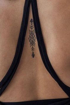 the back of a woman's neck with an arrow tattoo on it