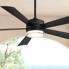 a ceiling fan that is lit up in front of a window with the light on