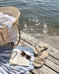 an open book and some sandals on a wooden dock