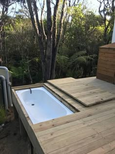 a hot tub sitting on top of a wooden deck next to a tree filled forest