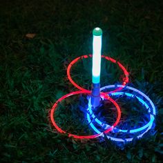 an illuminated hula hoop in the grass at night with two rings around it and one ring on top