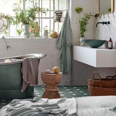 a bath room with a tub a sink and some plants in the window sill