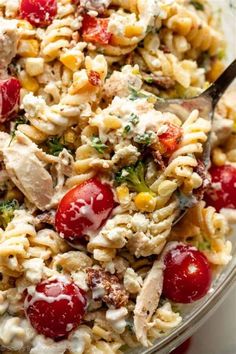 a bowl filled with pasta salad topped with chicken and cherry tomatoes