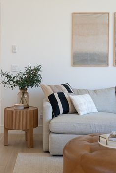 a living room with a couch, table and two paintings on the wall above it