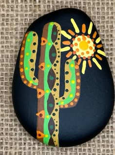 a painted rock with a cactus and sun on it