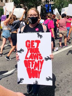 a woman holding up a sign that says get your lawns off my booy