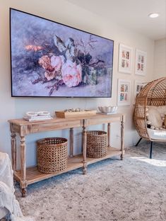 a living room with a large painting on the wall and wicker baskets under it