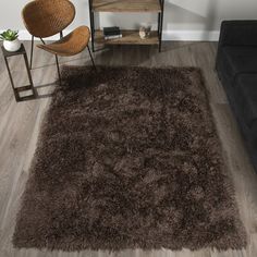 a living room with a black couch and brown rug