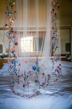 the bed is covered with sheer curtains and flowers