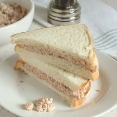 a sandwich cut in half sitting on top of a white plate next to a bowl of cereal