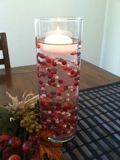 a candle that is sitting on a table next to some grapes and other fruit in a vase