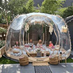 a group of people sitting around a table in a bubble tent