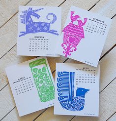 four calendars with different designs on them sitting on a wooden table next to each other