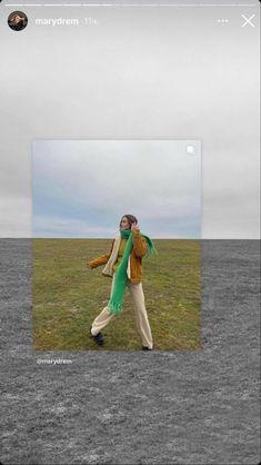 a man standing on top of a grass covered field holding a green scarf over his shoulder