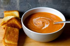 a bowl of tomato soup with grilled bread on the side