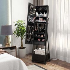 a black jewelry rack in a bedroom next to a bed