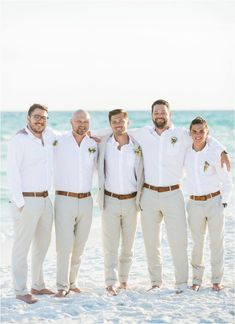 a group of men standing next to each other on top of a beach