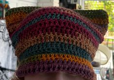 a close up of a person wearing a knitted hat with multicolored stripes