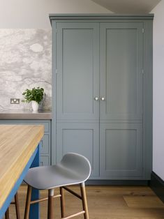 a kitchen with blue cabinets and stools next to a wooden table in front of it