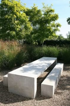 a concrete bench sitting on top of a gravel field