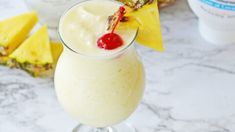 a pineapple drink in a glass with a cherry garnish on the top