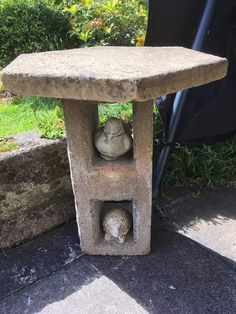 a stone bird bath with two birds in it's niche next to a flower pot