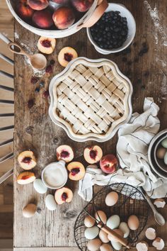 fresh peaches, plums, and other fruits are on the table with pie crust