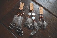 four feathers with tags attached to them sitting on a wooden floor next to each other