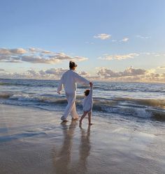 a man and child are walking on the beach