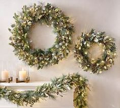 christmas wreaths and candles are arranged on the mantle