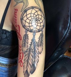 a woman's arm with a tattoo on it that has a dream catcher in it