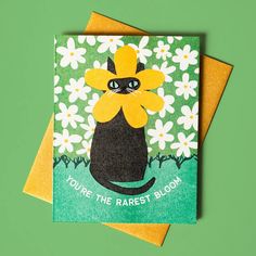 a card with an image of a black cat holding a yellow flower