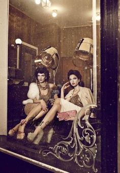 two women sitting on a bench in front of a mirror