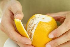 a person holding an orange on a plate with their hands over the top of it