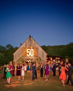 a group of people standing in front of a barn at night with the number 50 lit up