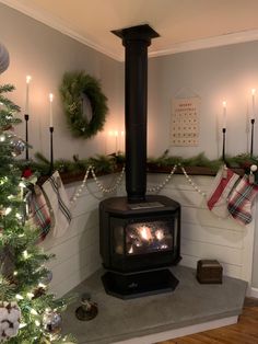 a fireplace with christmas stockings hanging on the wall and candles lit in front of it