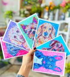 a person holding four cards with dogs painted on them