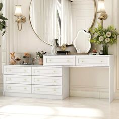 a white dresser with a large mirror and flowers in vases on top of it