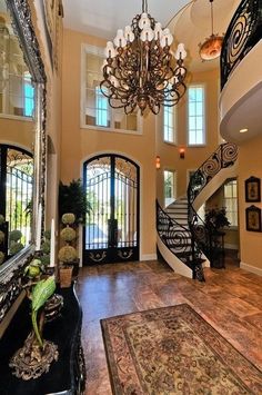 a large foyer with chandelier, mirror and staircase leading up to the second floor