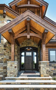 the front entrance to a large home with stone steps and wooden beams on each side